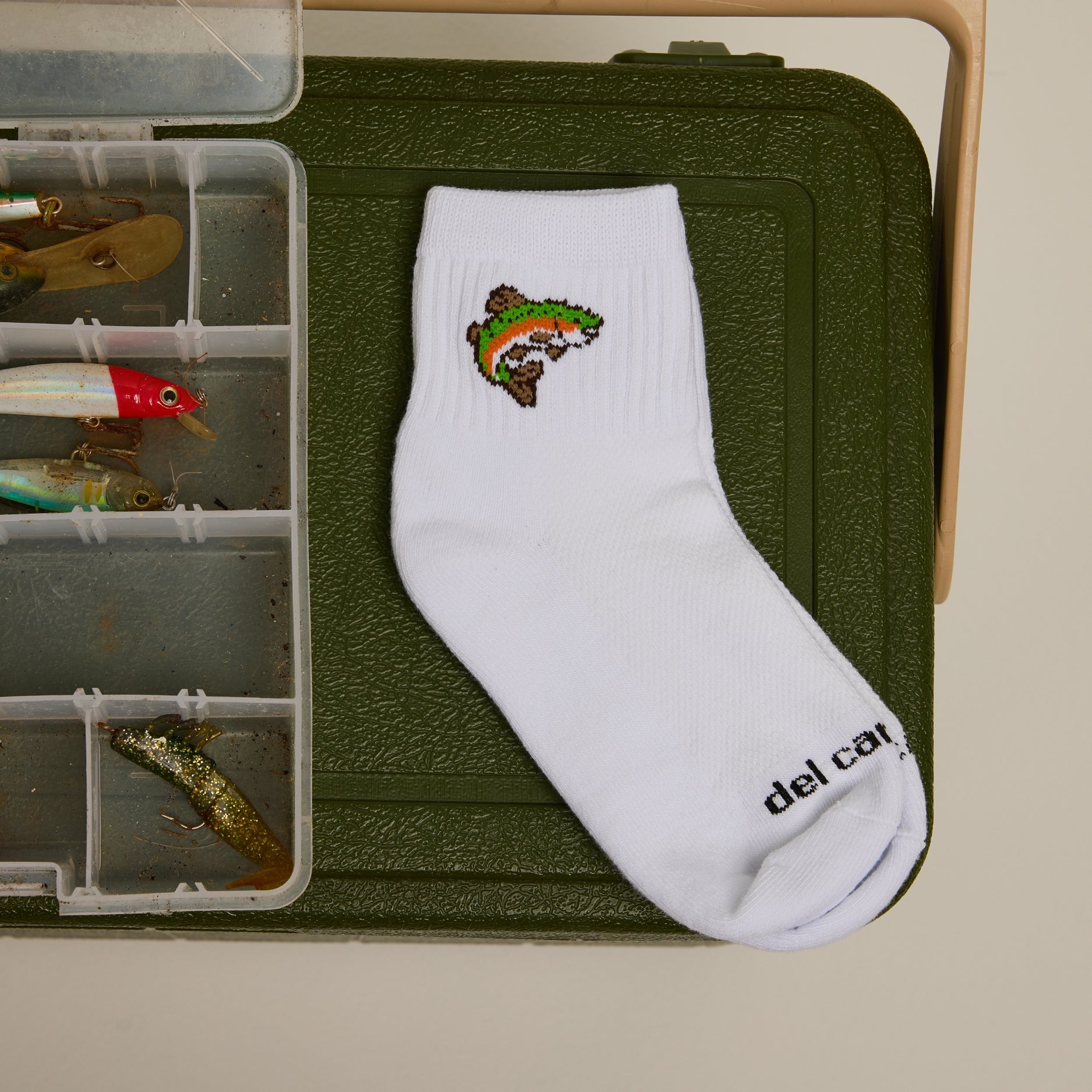 Del Campo Trout sock on a tackle box with fishing lures