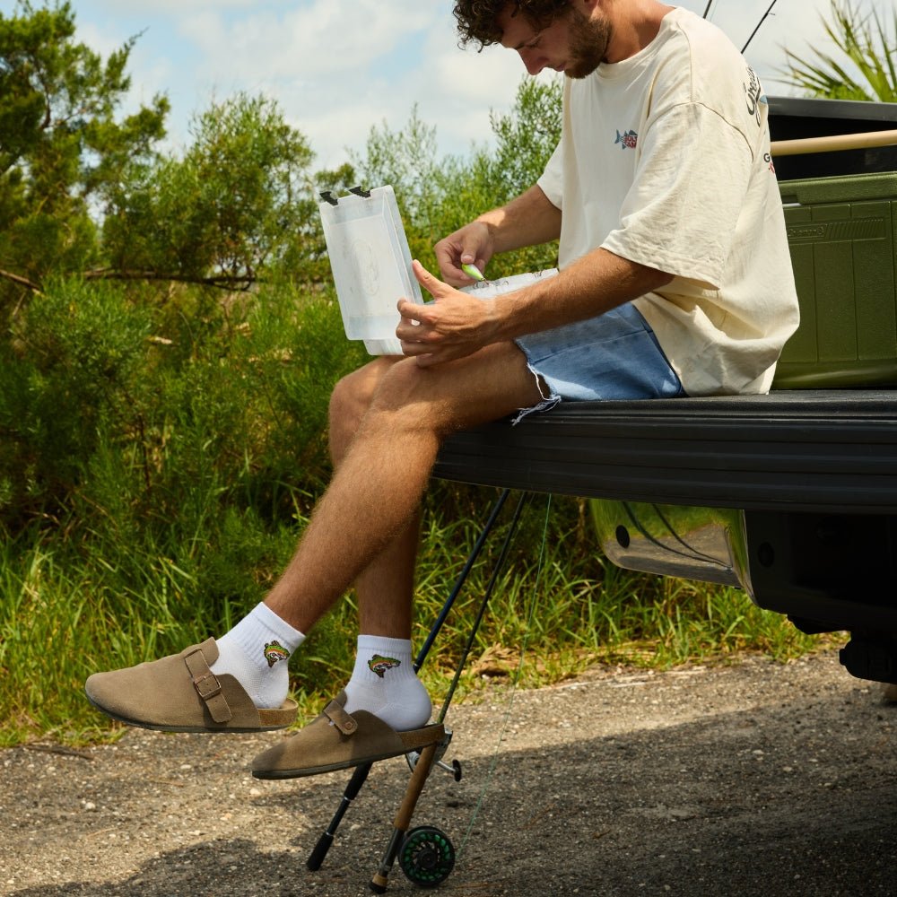 Man sitting outdoors wearing Del Campo Trout socks with clogs