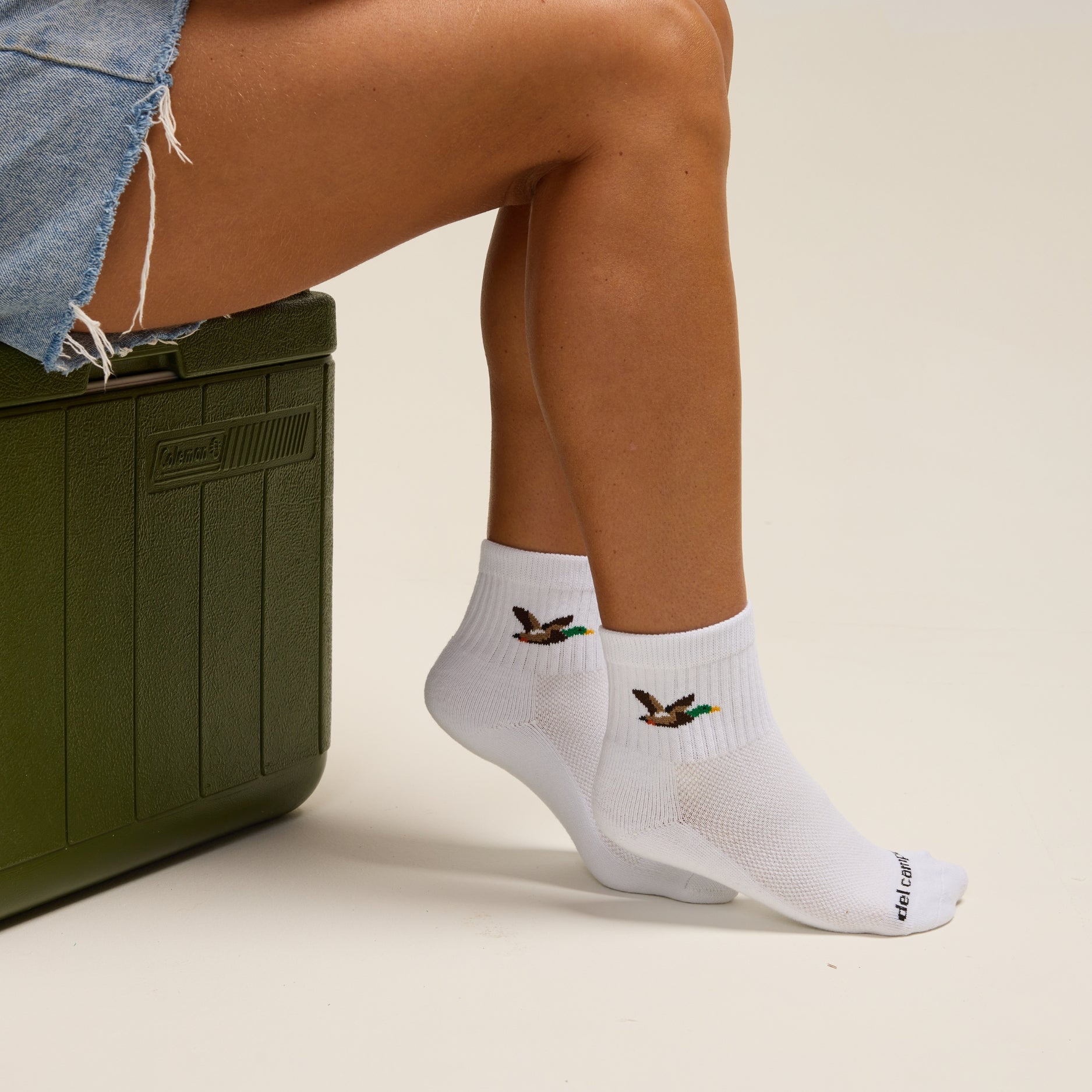 Del Campo Mallard socks worn beside a green cooler and golf ball