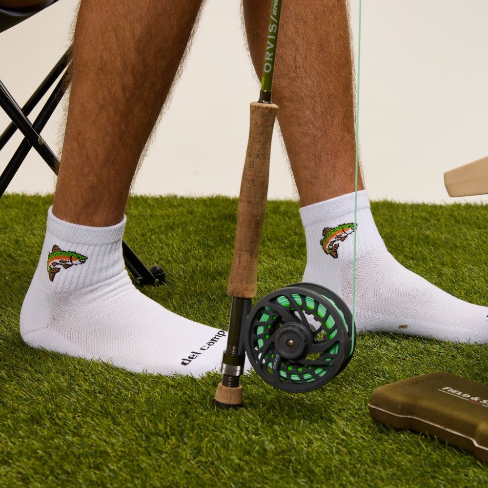 Del Campo Kids Trout socks worn on grass beside a fly rod and reel