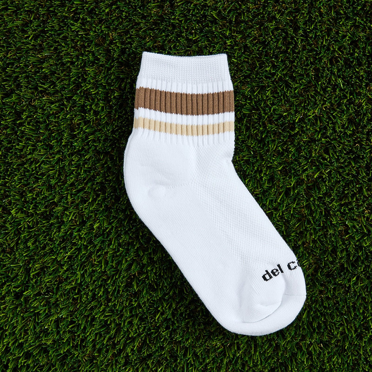 Del Campo Coffee Stripes golf socks, flat lay on grass