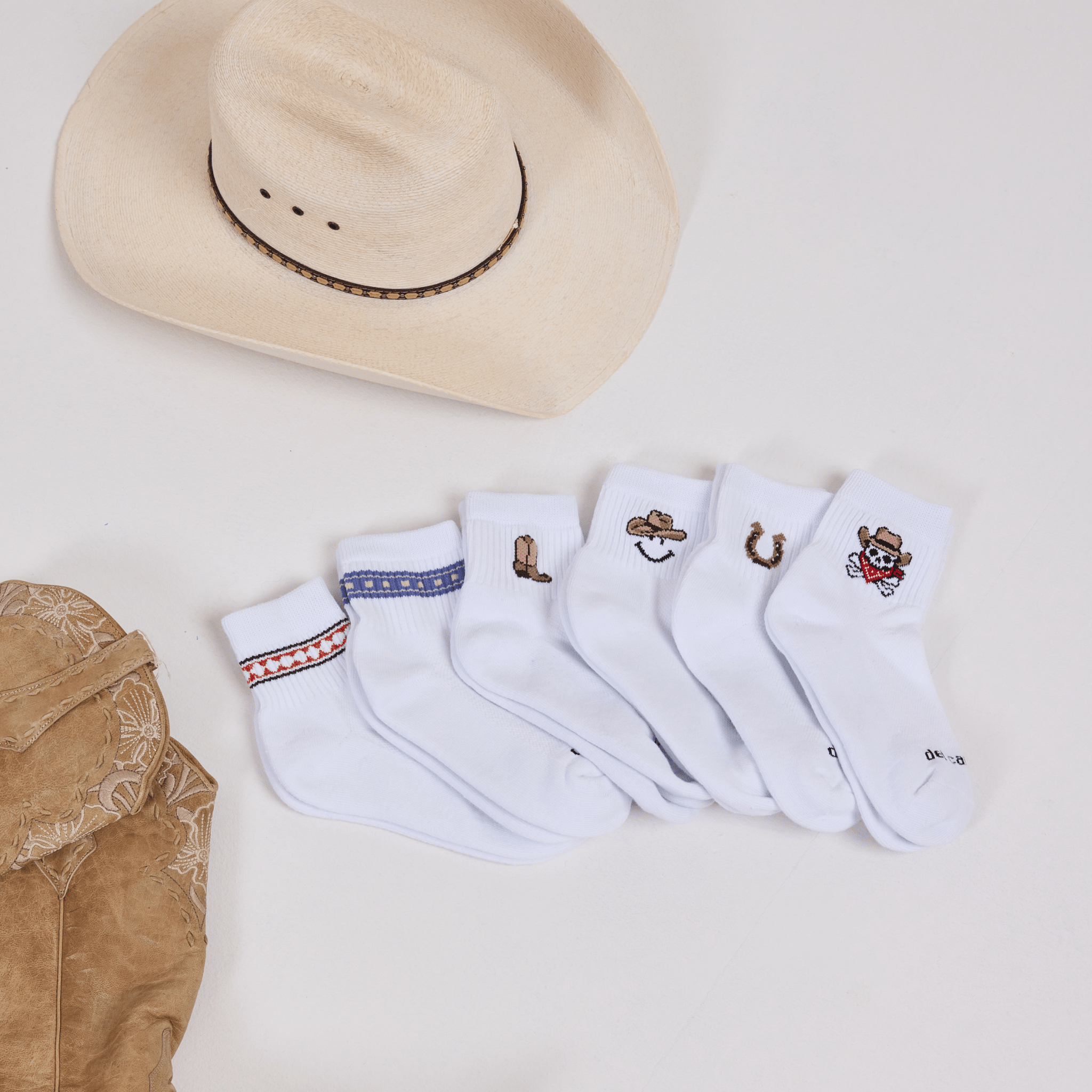Del Campo Western Pack socks styled with a cowboy hat and leather boots, fanned out to show all six designs.