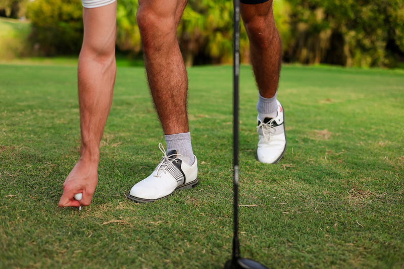 Golfer placing a tee in grey Del Campo blank socks