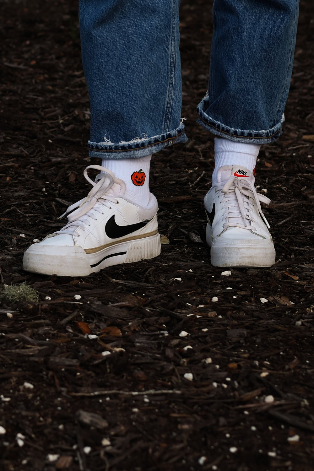 Del Campo Jack-O'-Lantern Halloween golf socks worn with white sneakers on dark mulch