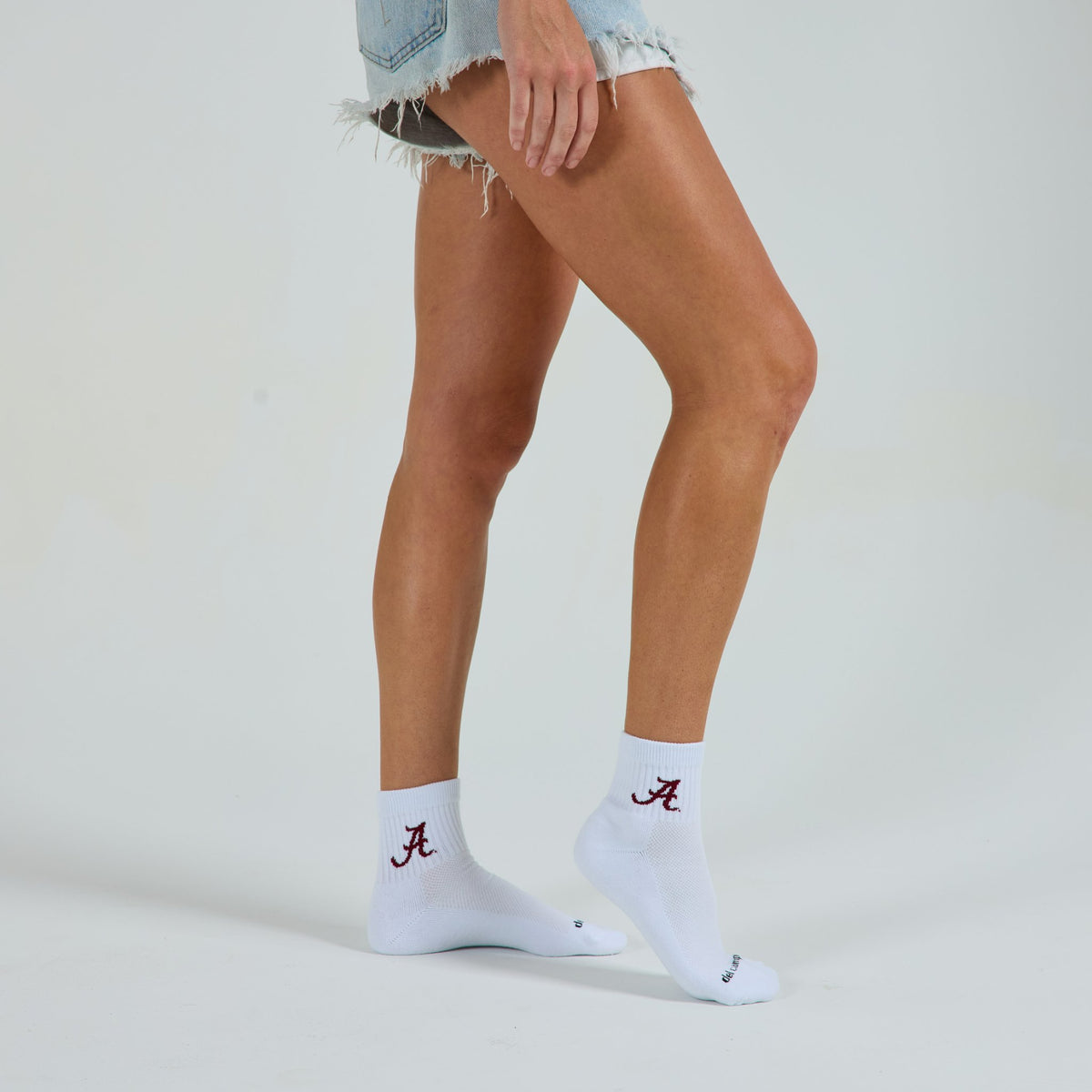 Woman wearing Del Campo Alabama Crimson Tide golf socks, studio shot, no shoes