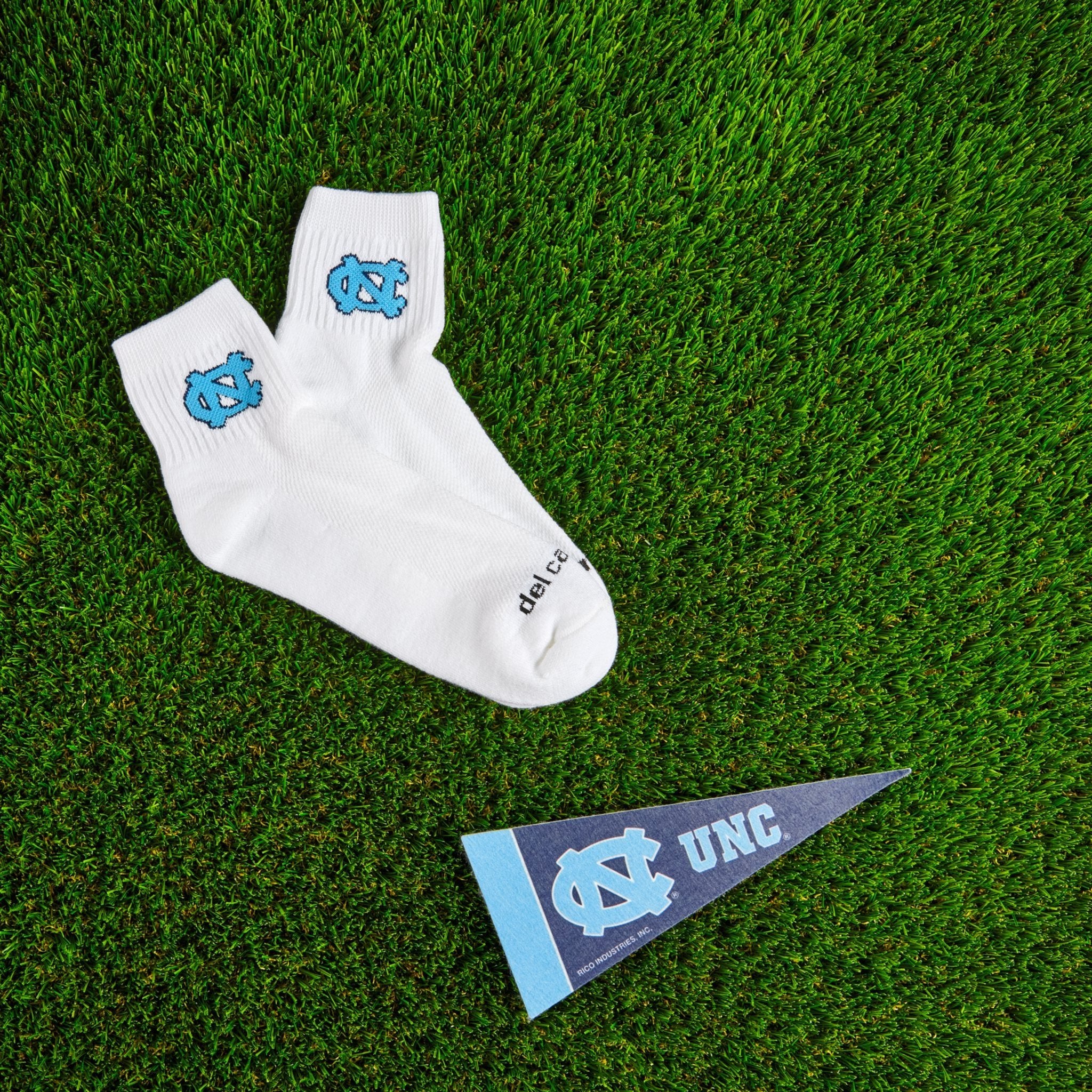 Del Campo North Carolina Interlocking NC golf socks on turf with a team pennant