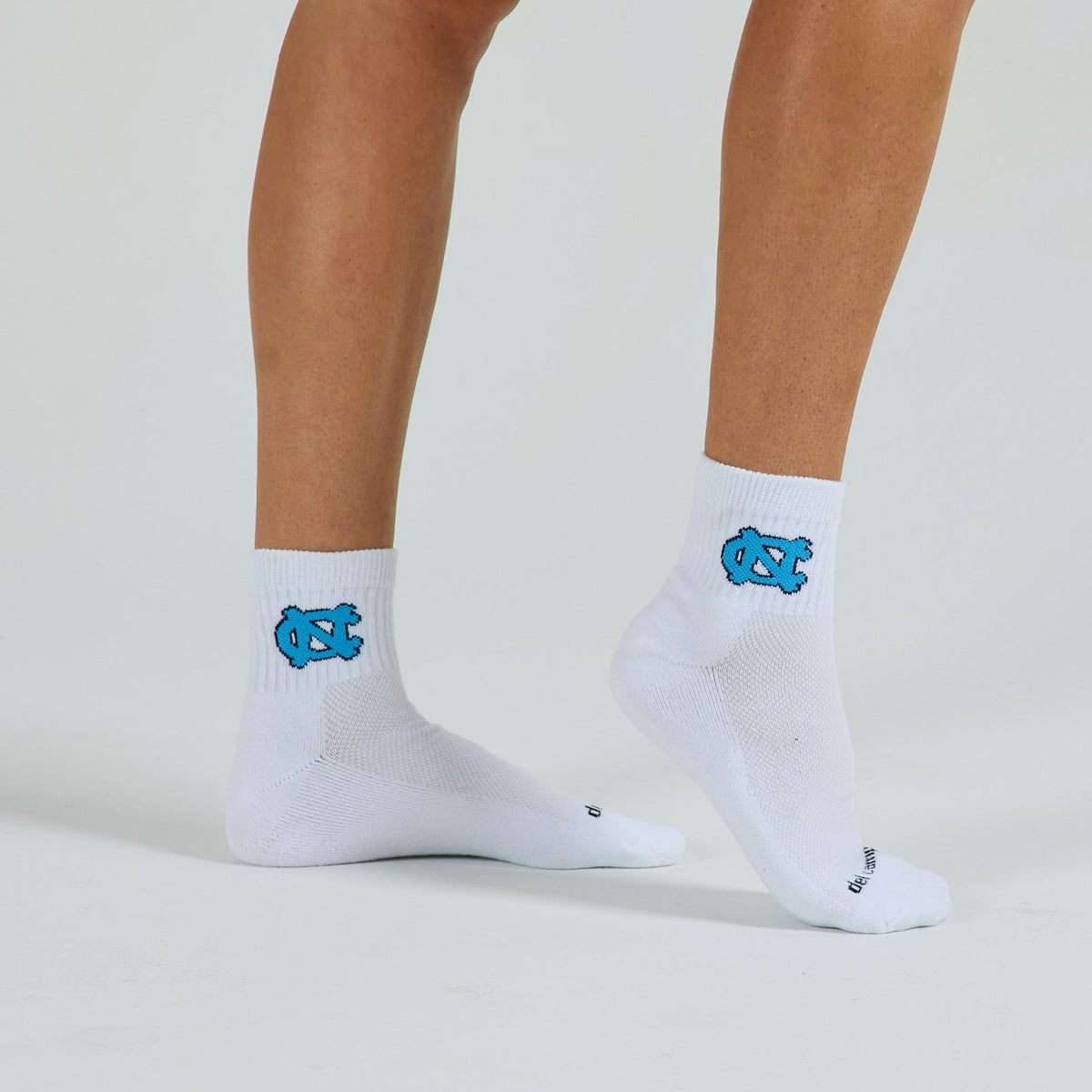 Woman wearing Del Campo North Carolina Interlocking NC golf socks, studio shot, no shoes