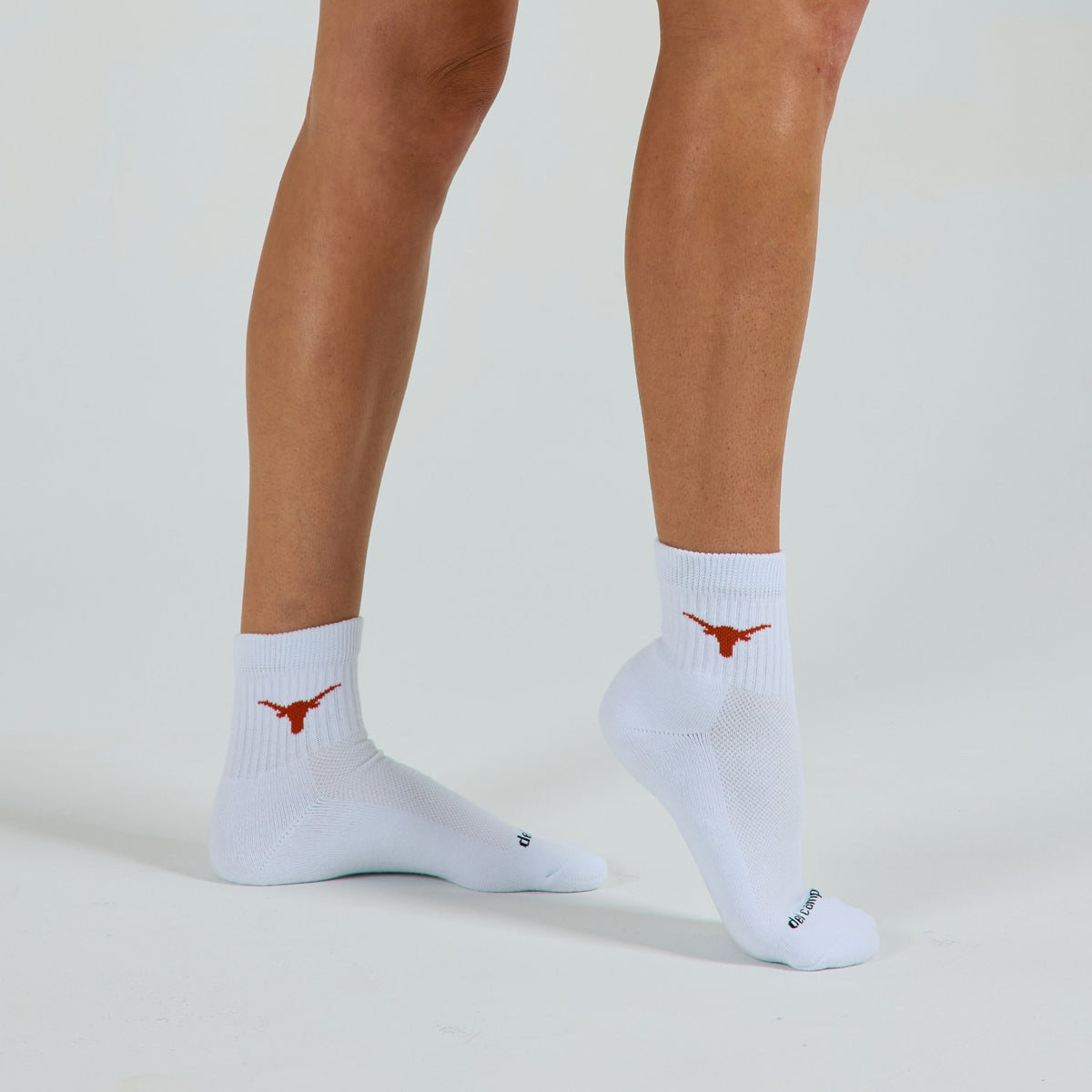 Woman wearing Del Campo Texas Longhorns golf socks, studio shot, no shoes