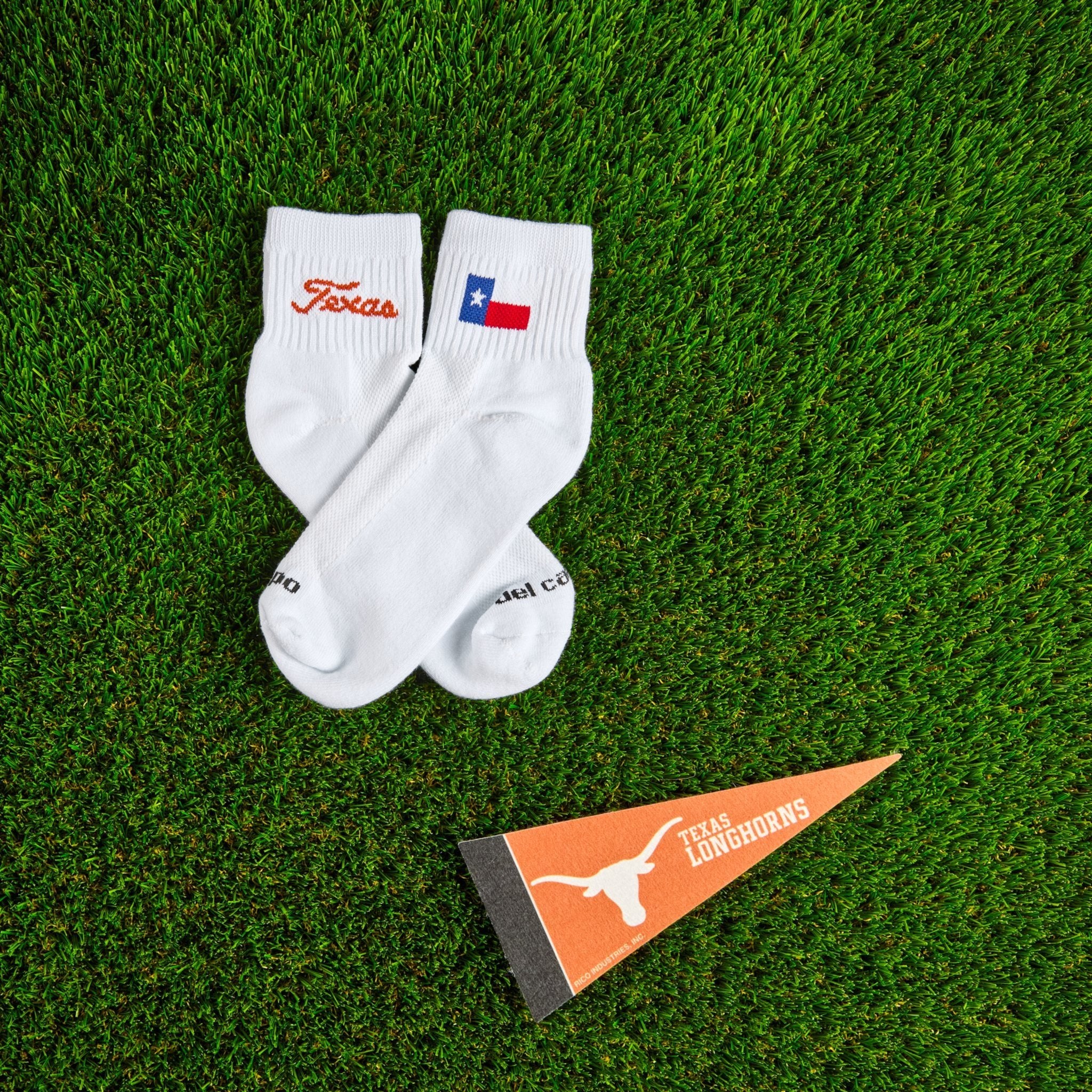 Del Campo Texas Longhorns Script golf socks on turf beside the Texas state flag design