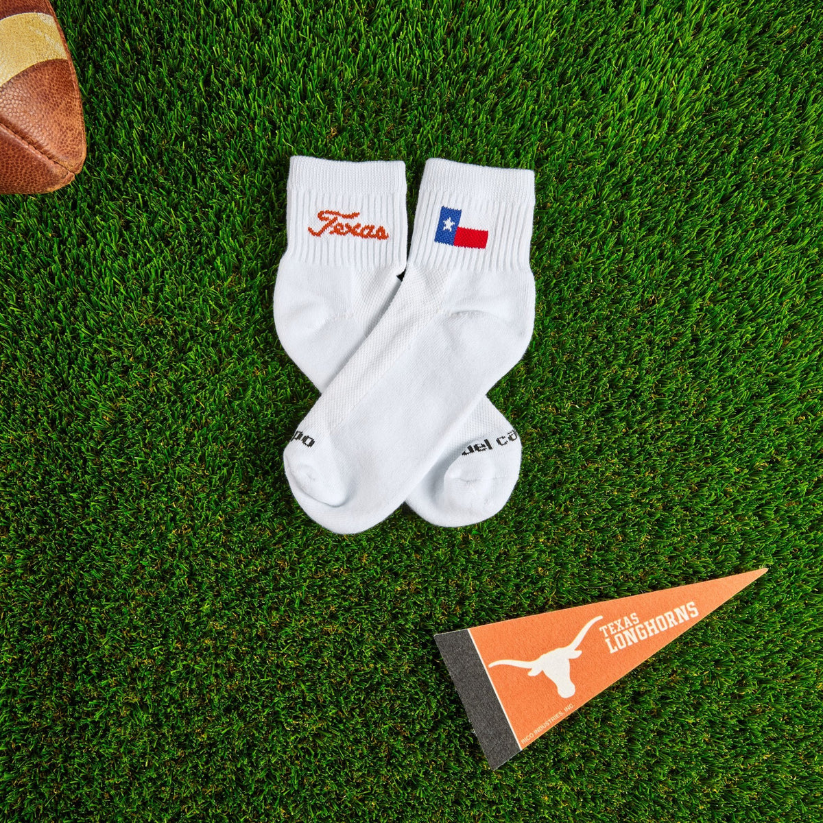 Del Campo Texas Longhorns Script golf socks on turf beside the Texas state flag design