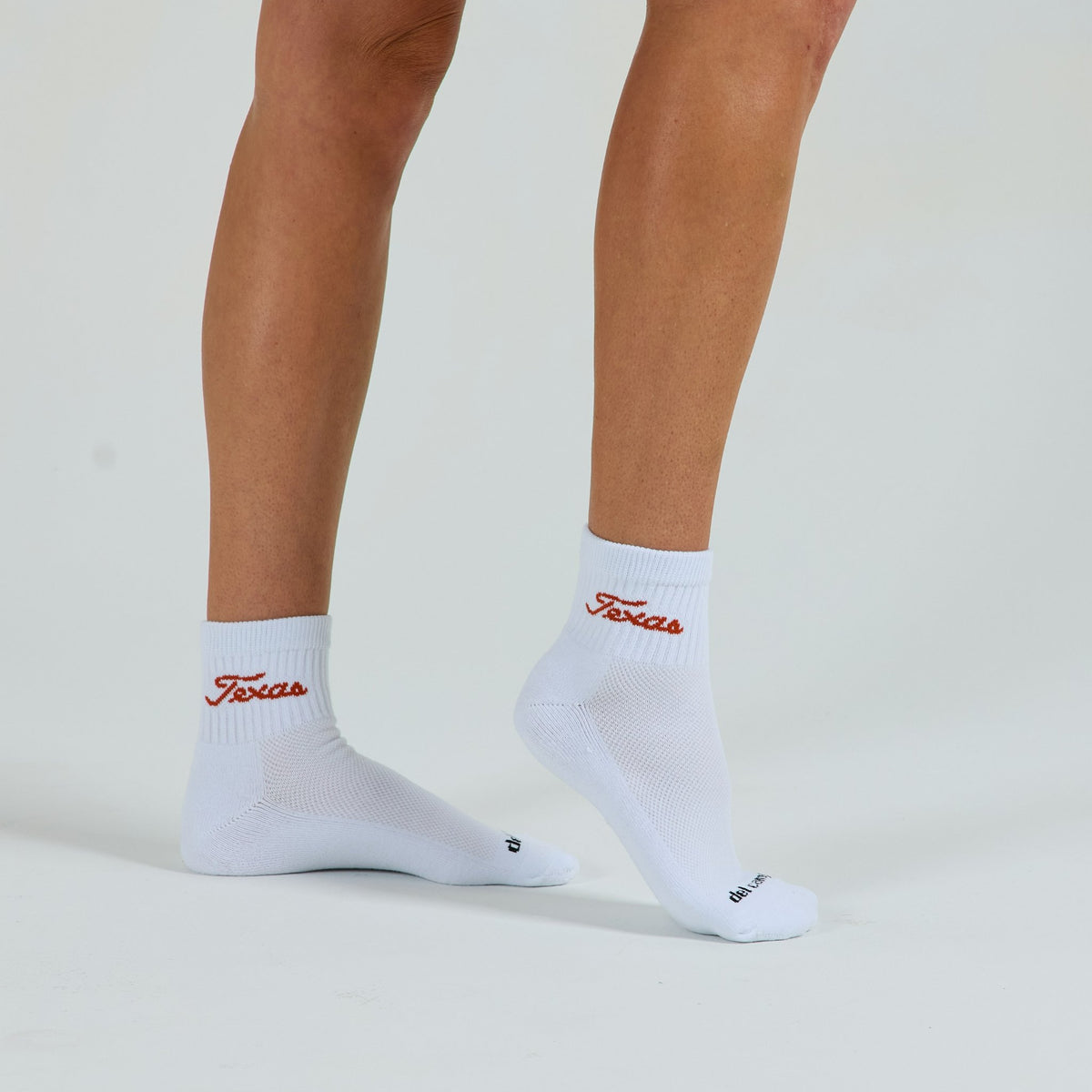 Woman wearing Del Campo Texas Longhorns Script golf socks, studio shot, no shoes
