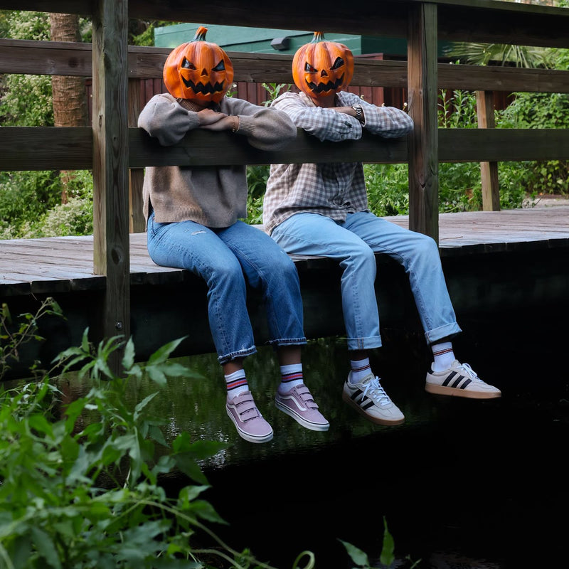 Two jack-o'-lantern heads on a bridge rail wearing Halloween stripe socks