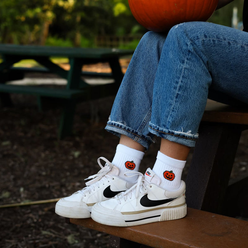 Jack-O'-Lantern socks with white sneakers on a picnic bench