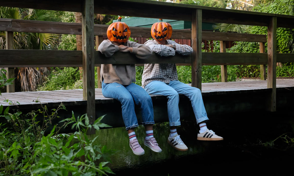Two jack-o'-lantern heads on a bridge wearing Del Campo Halloween socks