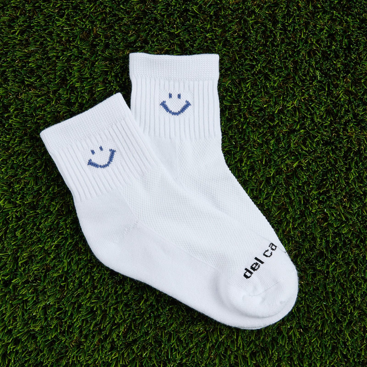 Del Campo Denim Smiley golf socks, flat lay on grass