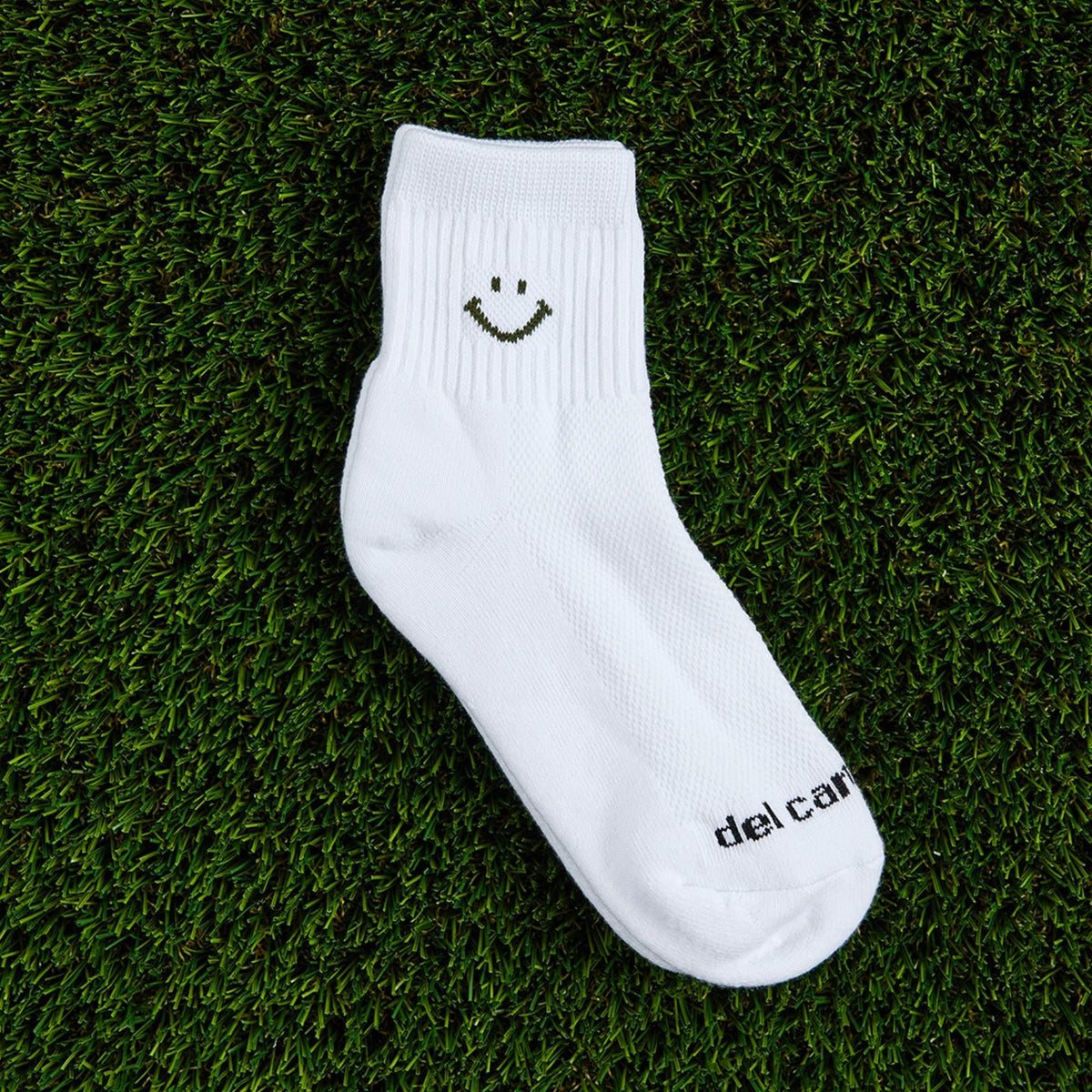 Del Campo Forest Smiley golf socks, flat lay on grass