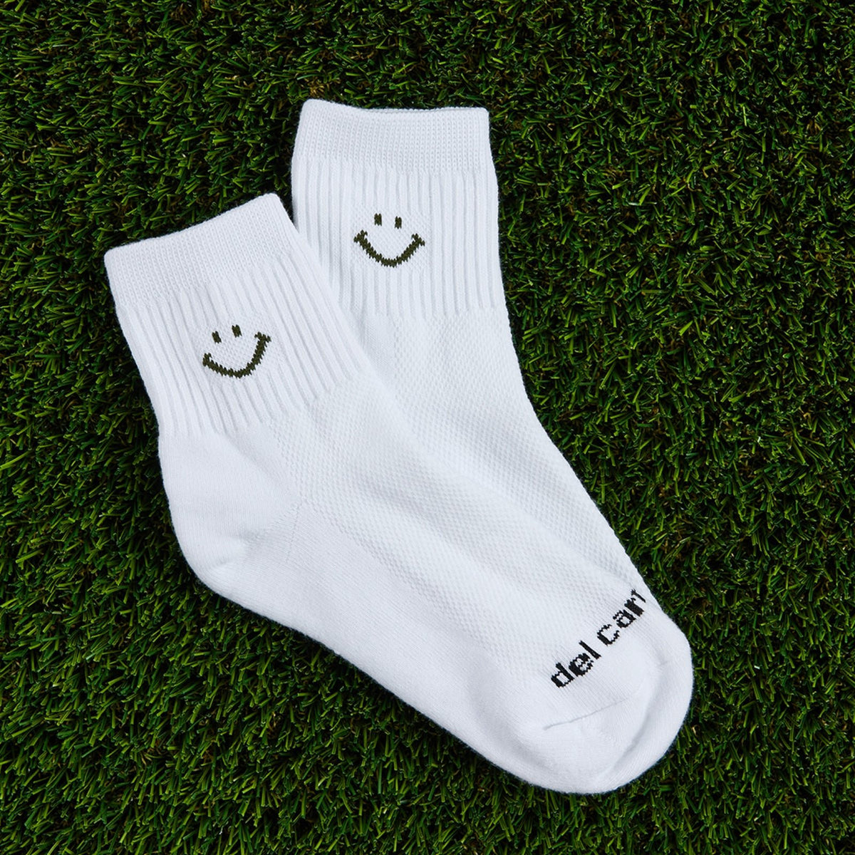 Del Campo Forest Smiley golf socks, flat lay on grass