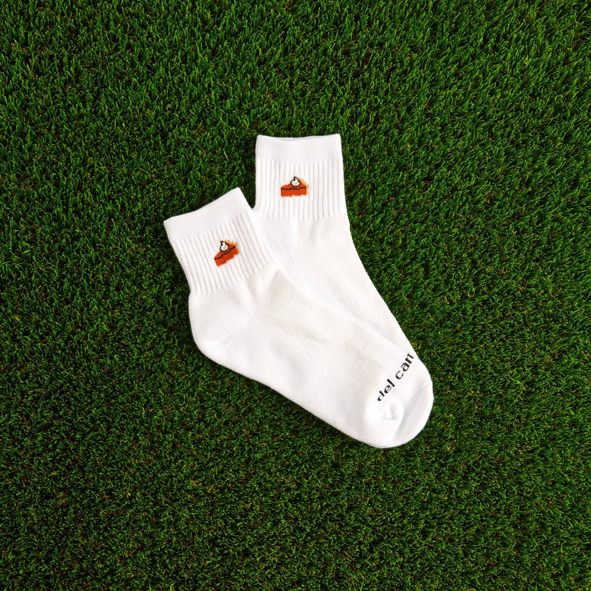 Del Campo Pumpkin Pie Thanksgiving golf socks, white quarter socks with a knit slice of pumpkin pie, pair on grass