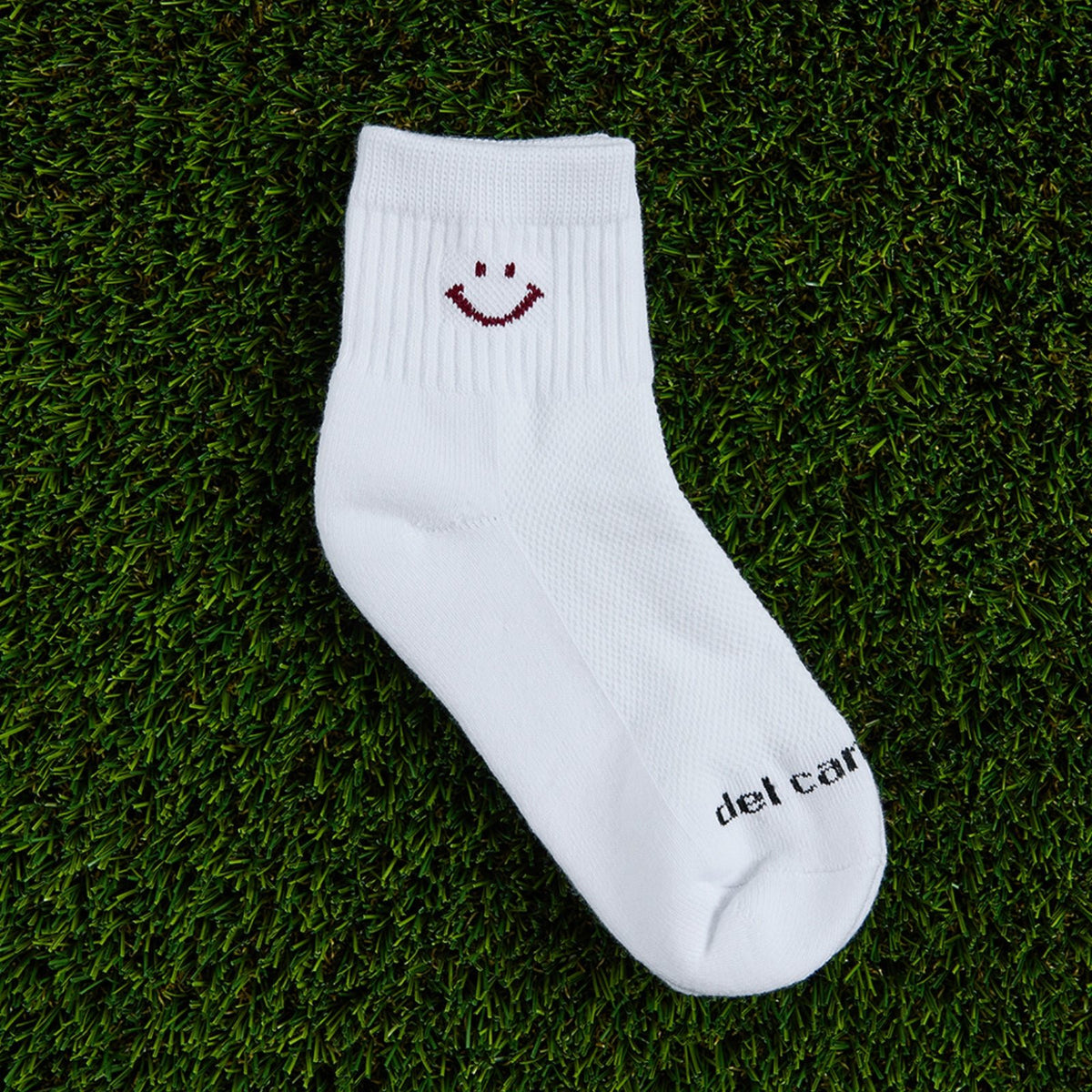 Del Campo Cardinal Smiley golf socks, flat lay on grass