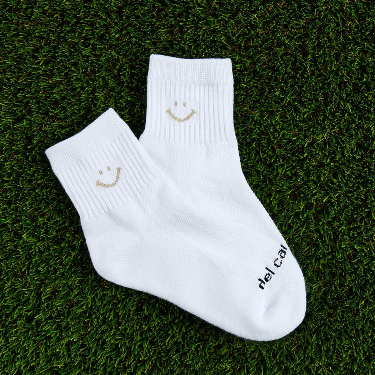 Del Campo Oatmeal Smiley golf socks, flat lay on grass