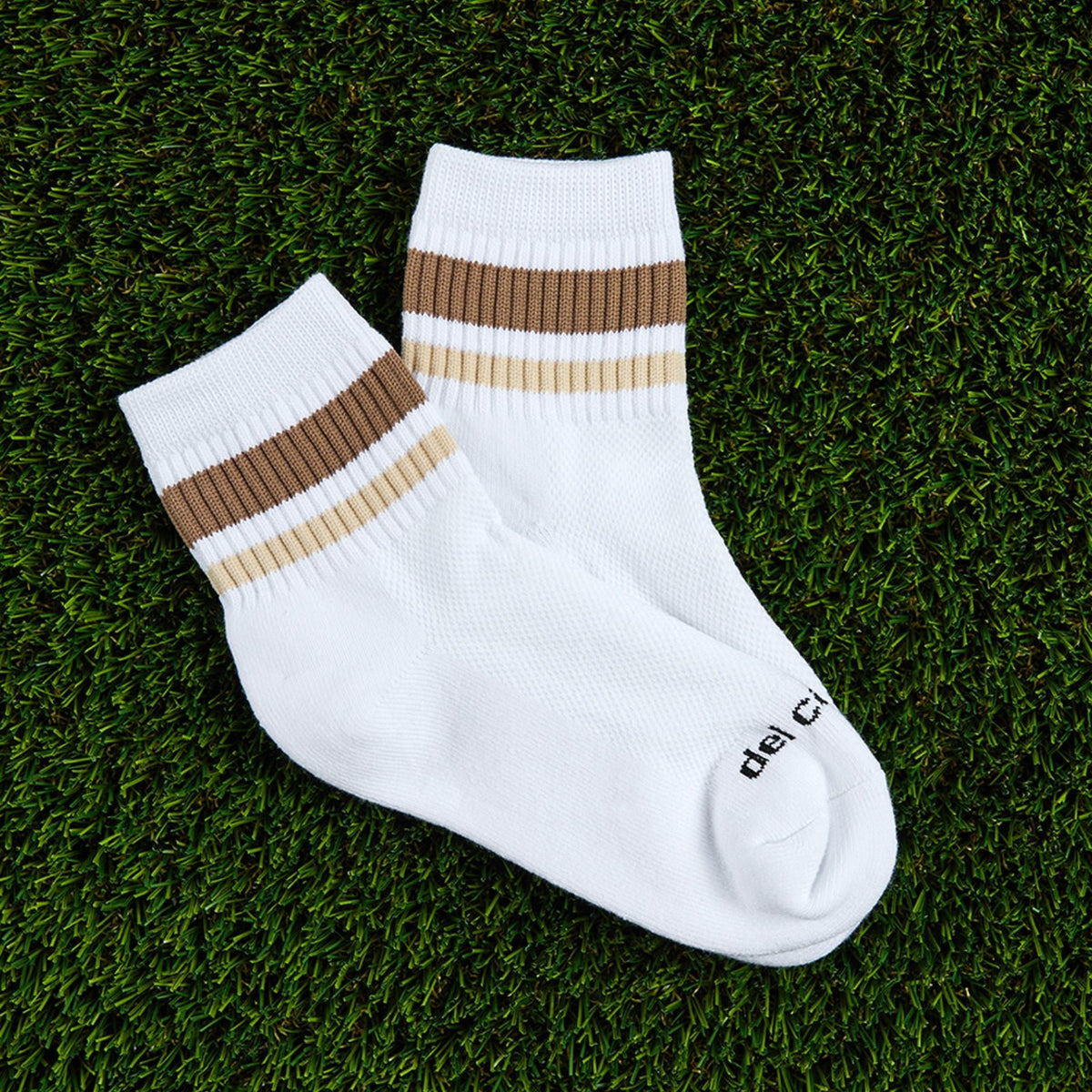 Del Campo Coffee Stripes golf socks, flat lay on grass