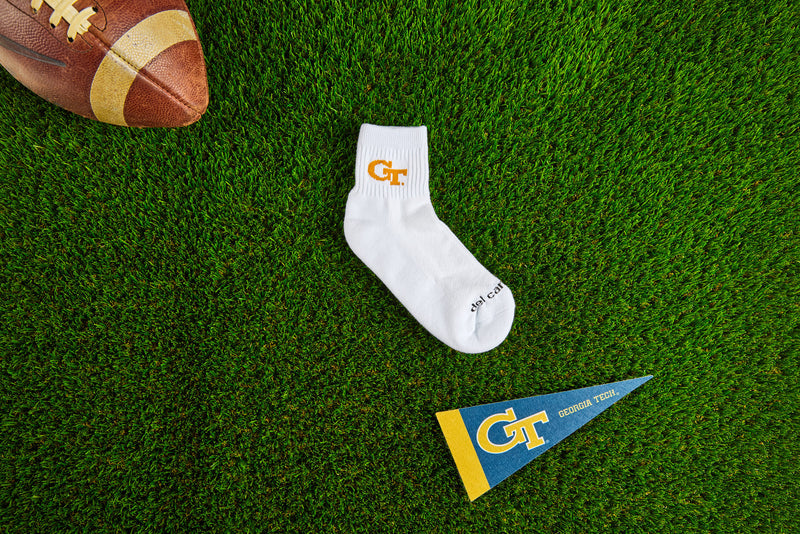 Officially licensed Del Campo Georgia Tech Yellow Jackets socks laid out on turf.