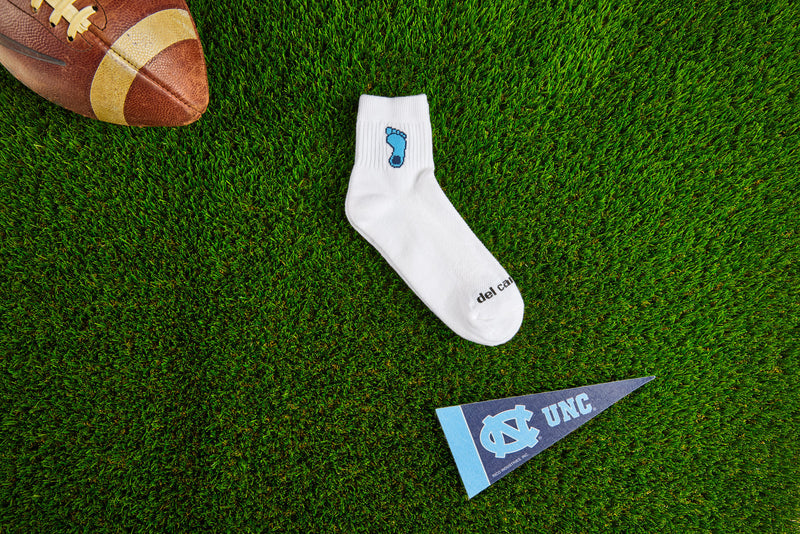 Officially licensed Del Campo North Carolina Tar Heels socks laid out on turf.