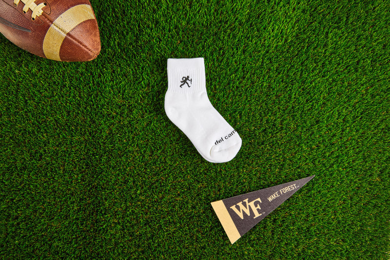 Officially licensed Del Campo Wake Forest Demon Deacons socks laid out on turf.