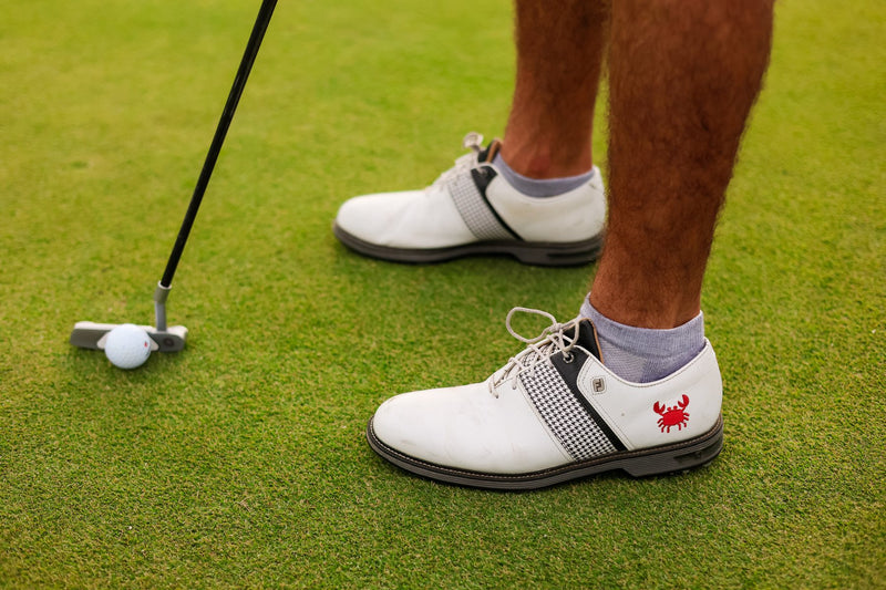 Golfer lining up a putt in grey Del Campo blank lowcut socks