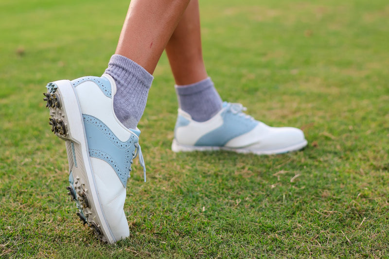 Close up of grey Del Campo blank socks with golf shoes on the grass