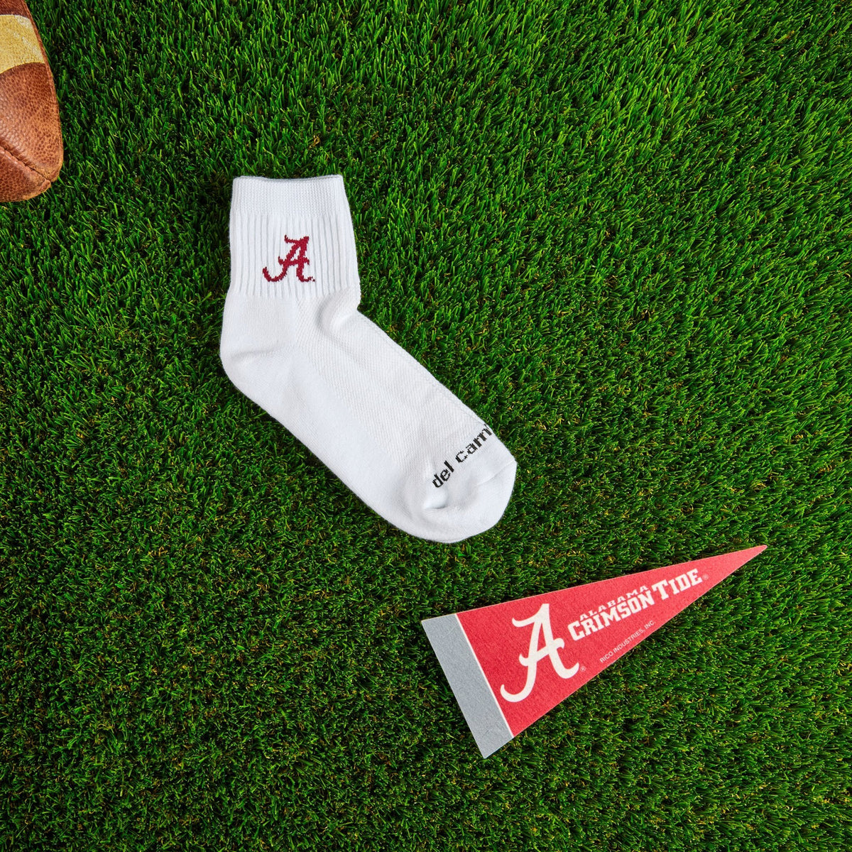 Flat lay of Del Campo Alabama Crimson Tide golf socks with game-day props