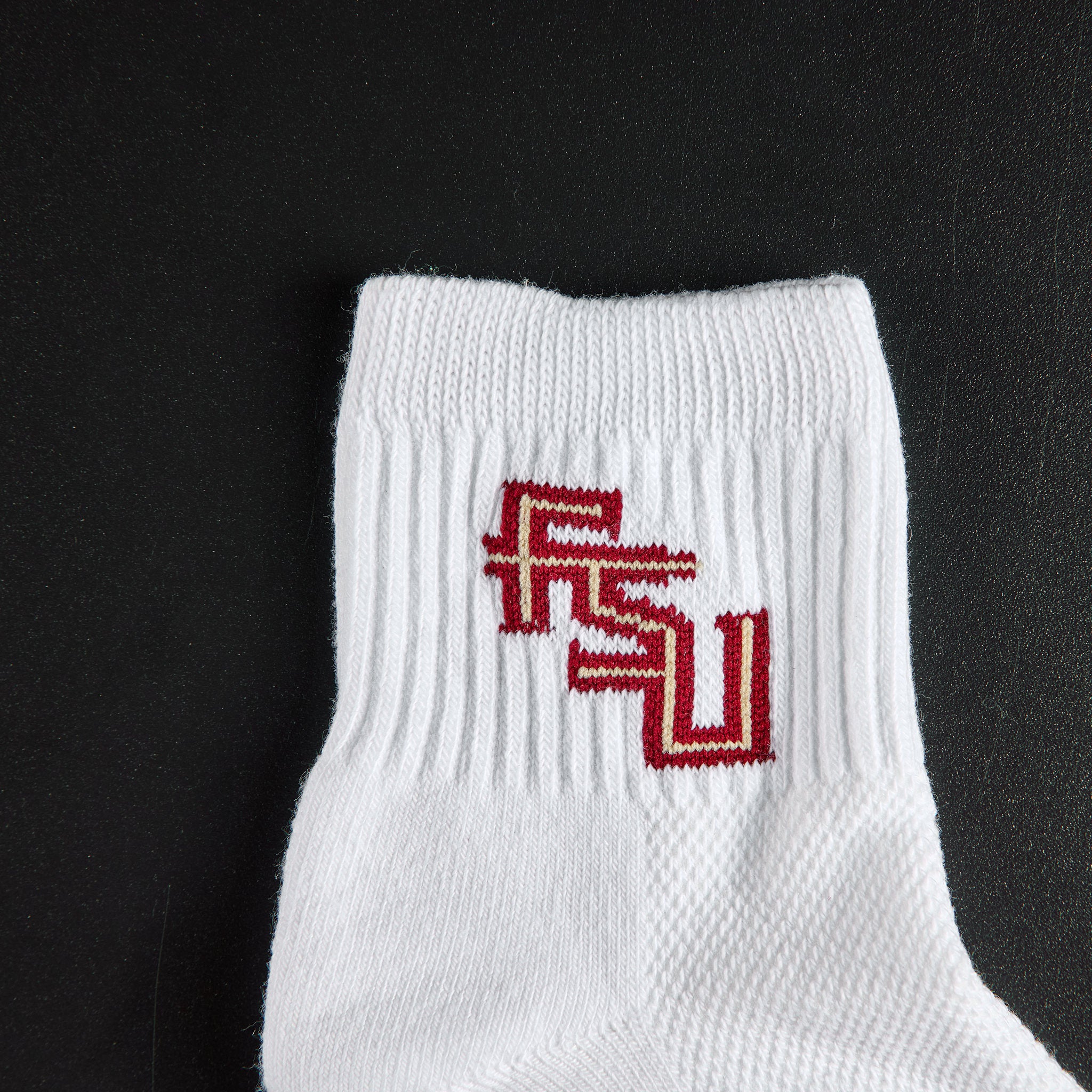 Close-up of the garnet and gold FSU interlock on Del Campo Florida State Script golf socks
