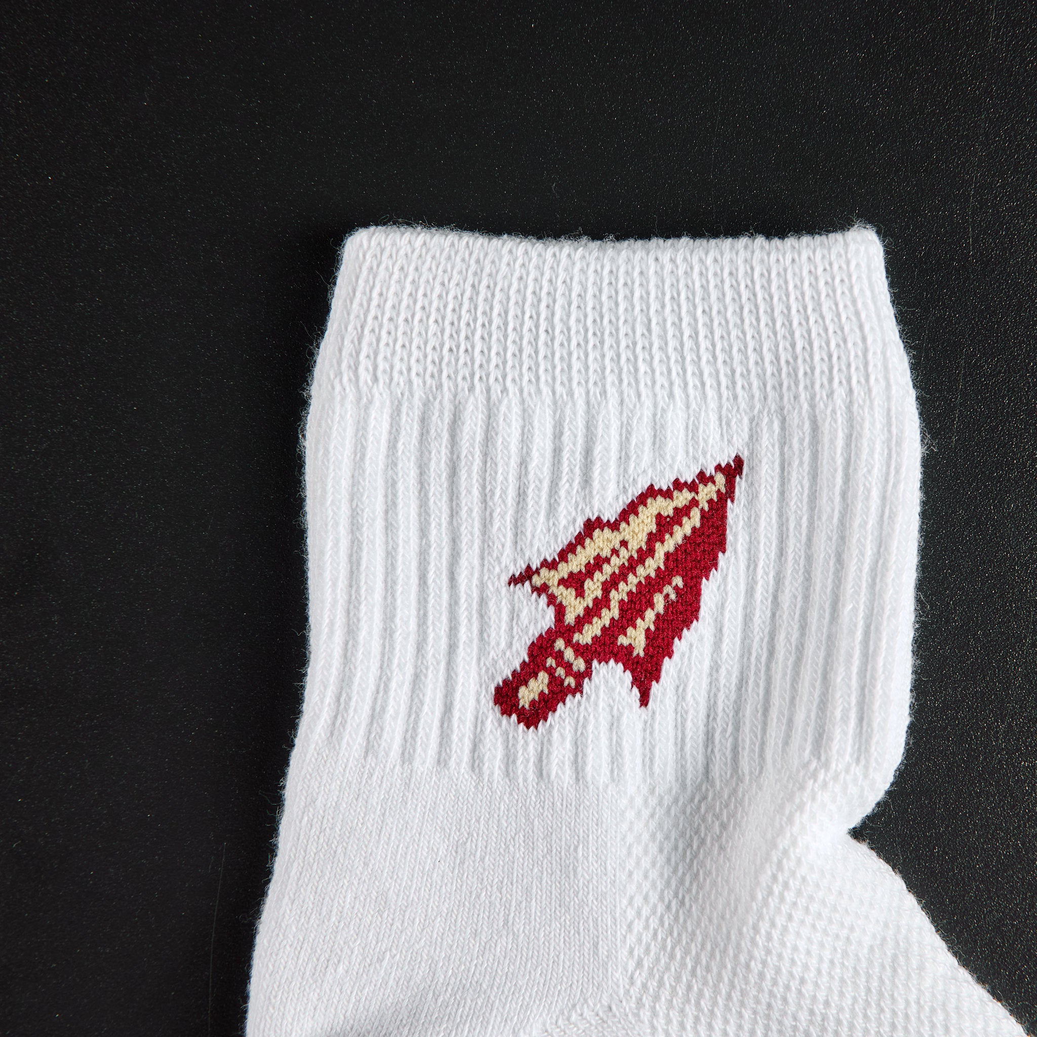 Close-up of the garnet and gold Seminole spear-arrowhead on Del Campo Florida State Spear golf socks