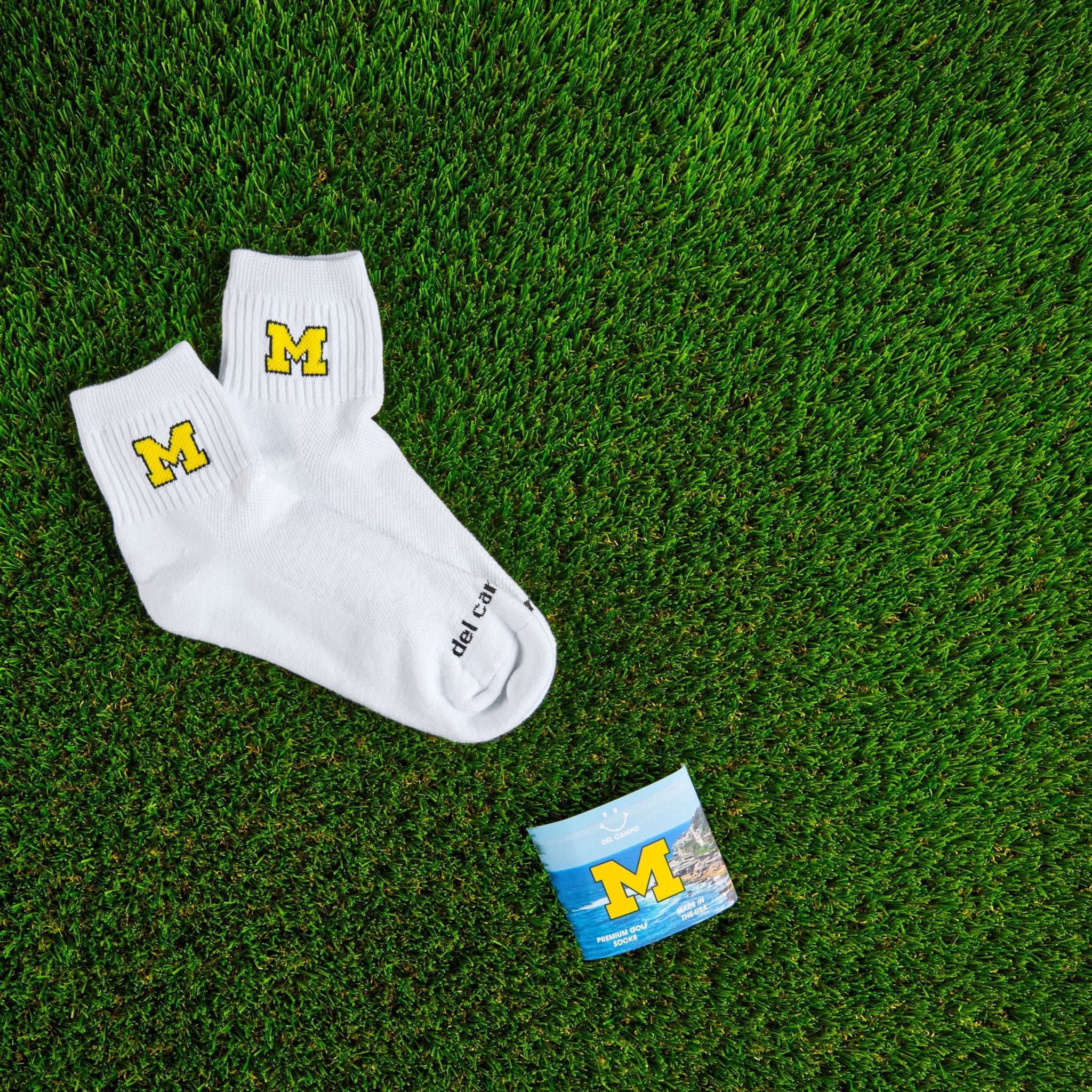 Del Campo Michigan Maize golf socks on turf with a team pennant