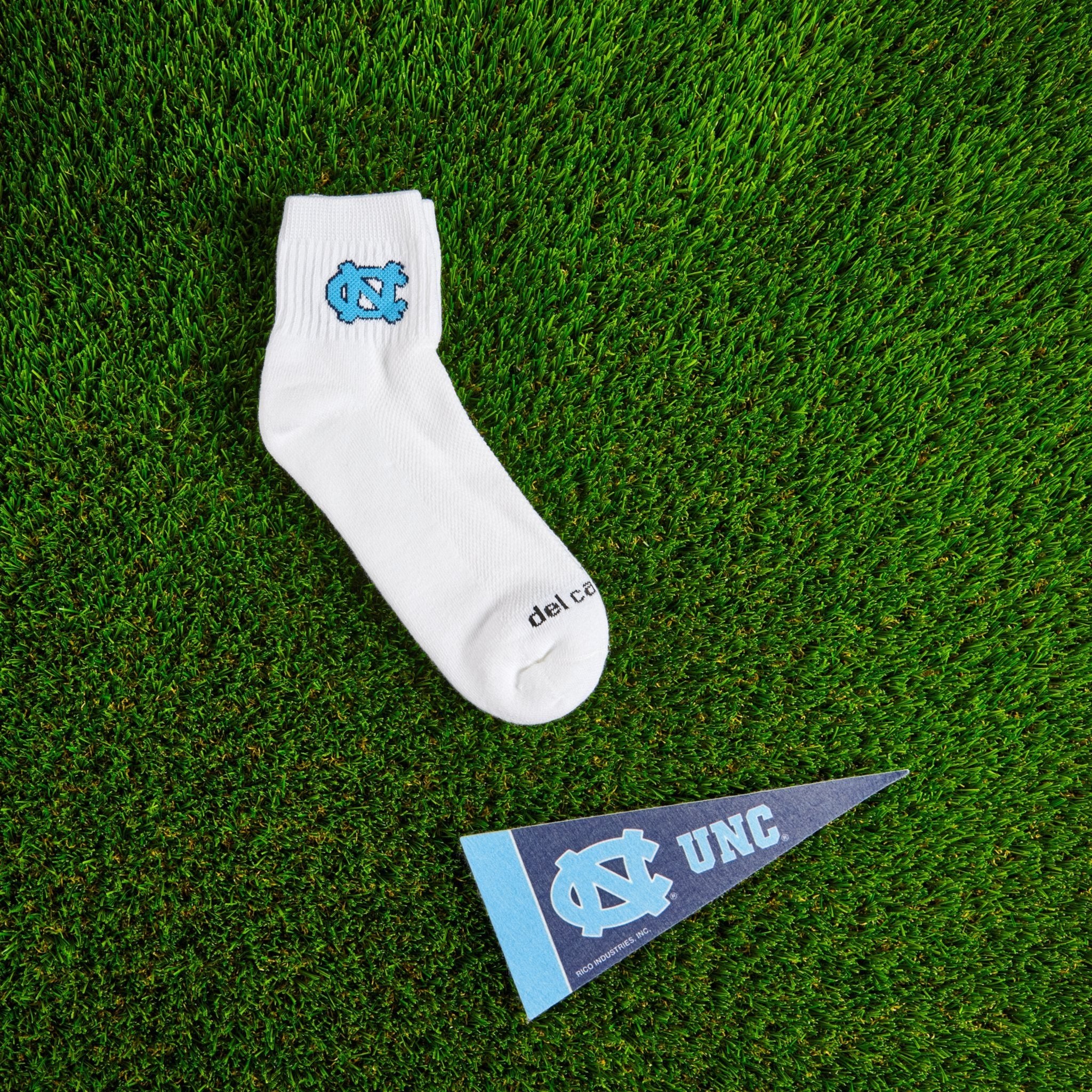 Flat lay of Del Campo North Carolina Interlocking NC golf socks with game-day props