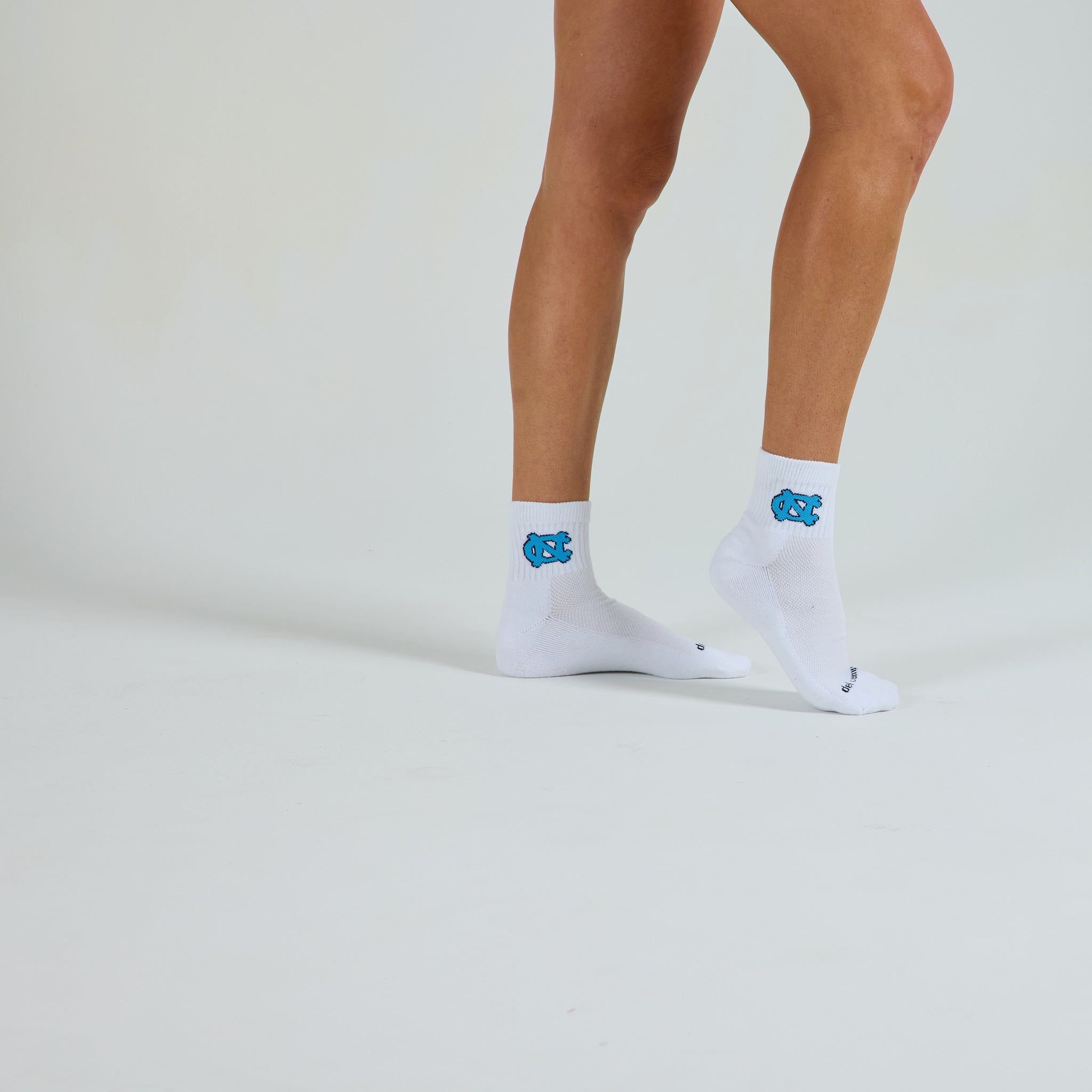 Woman wearing Del Campo North Carolina Interlocking NC golf socks, studio shot, no shoes