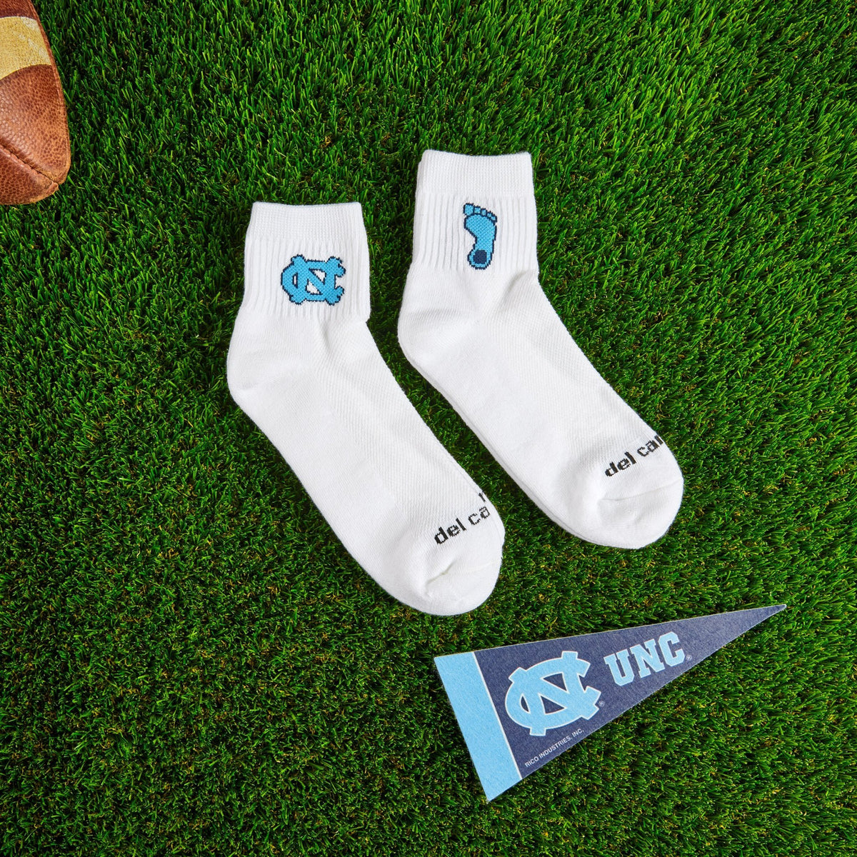 Flat lay of Del Campo North Carolina Pack golf socks with game-day props