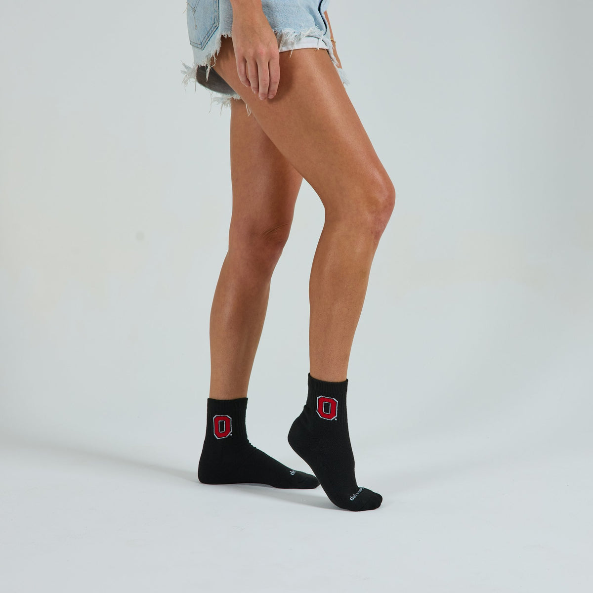 Woman wearing Del Campo Ohio State Night Mode golf socks, studio shot, no shoes