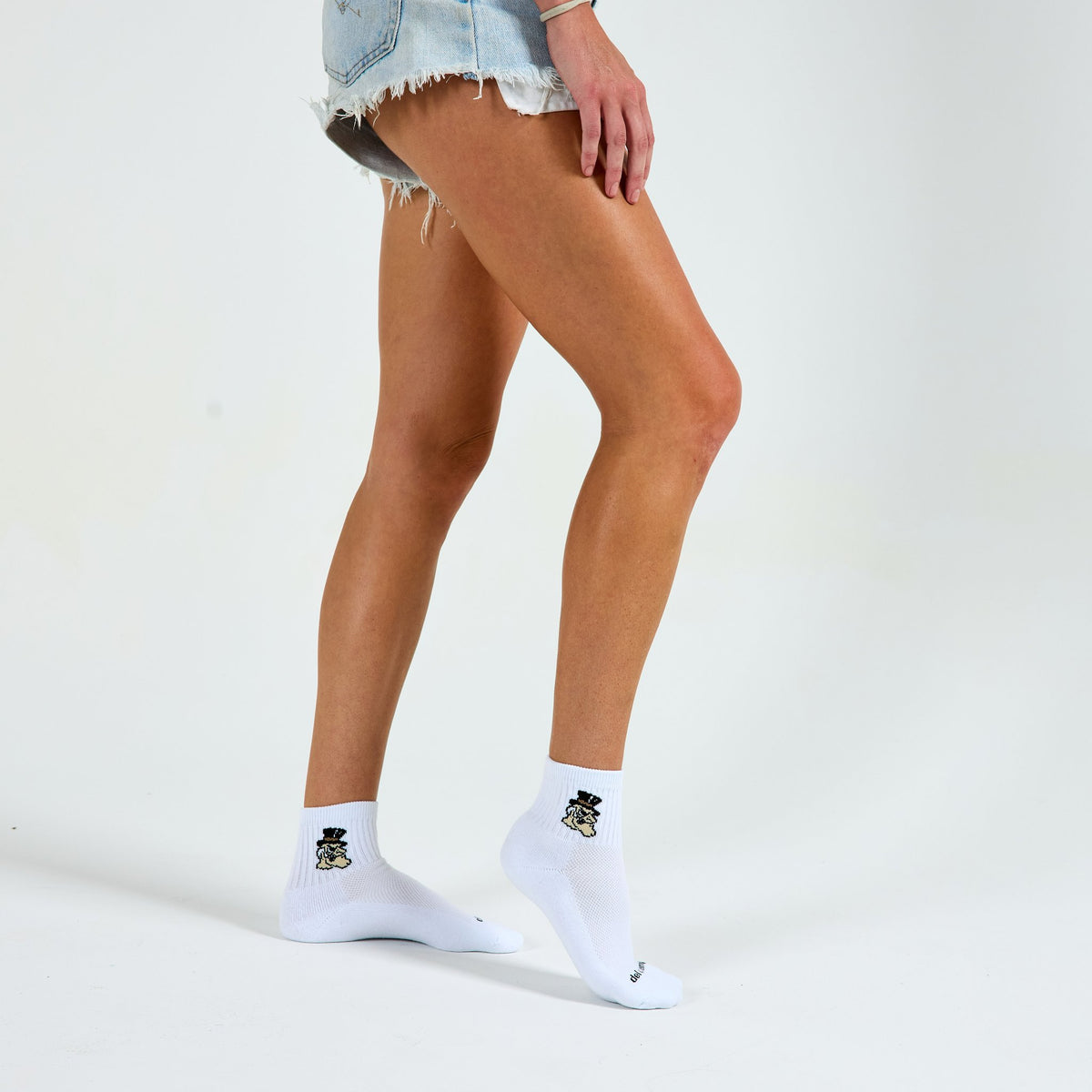 Woman wearing Del Campo Wake Forest Demon Deacons golf socks, studio shot, no shoes