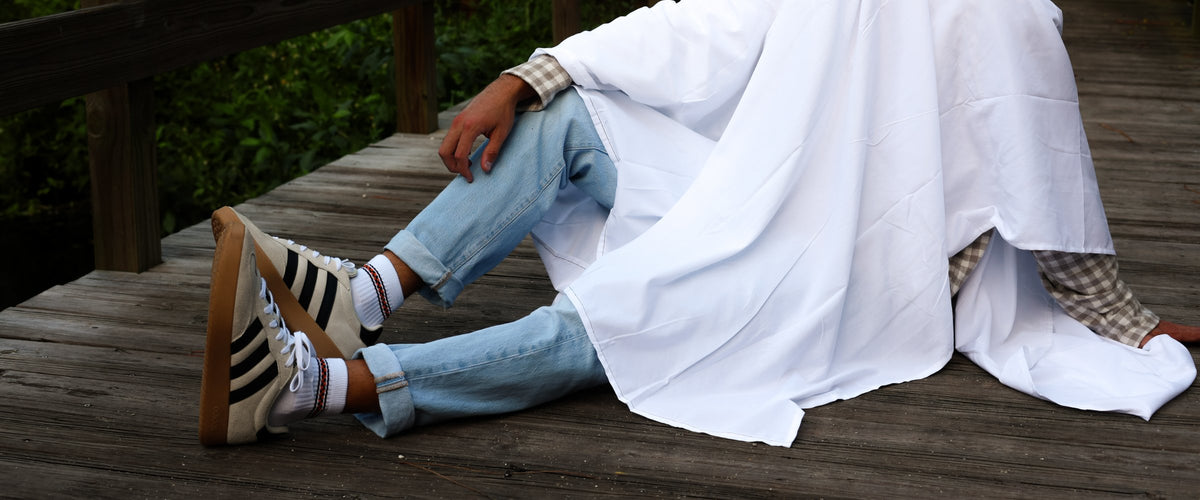 Ghost in a white sheet sitting on a boardwalk in Del Campo Halloween stripe socks
