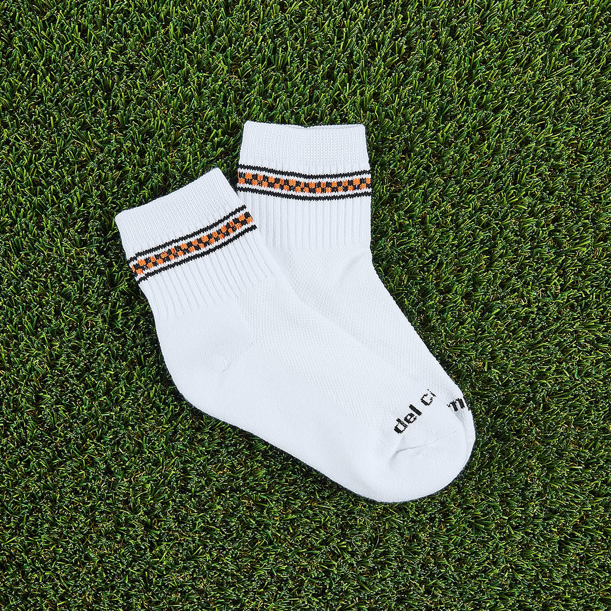 Del Campo Halloween Checkered Stripe Halloween golf socks, white quarter socks with a black and orange checkered stripe, pair on grass
