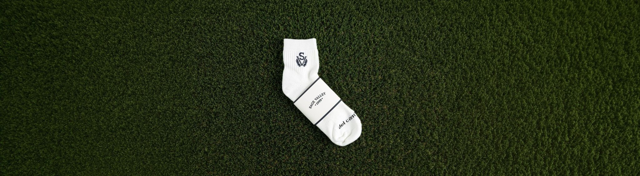 Custom logo golf sock with woven club logo and custom packaging wrap on grass