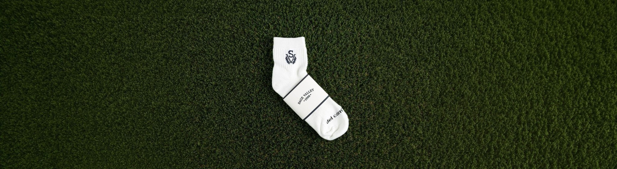 Custom logo golf sock with woven club logo and custom packaging wrap on grass